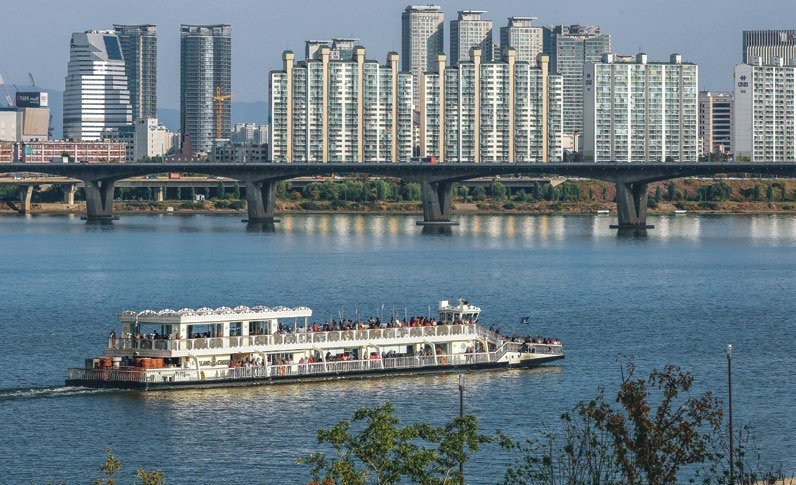 Visitors relaxing beside the Han River with the Seoul skyline
