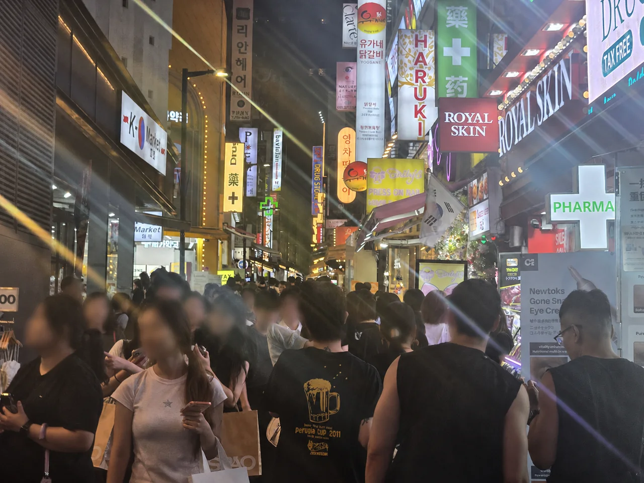 Busy Myeongdong shopping street at night with street food visitors