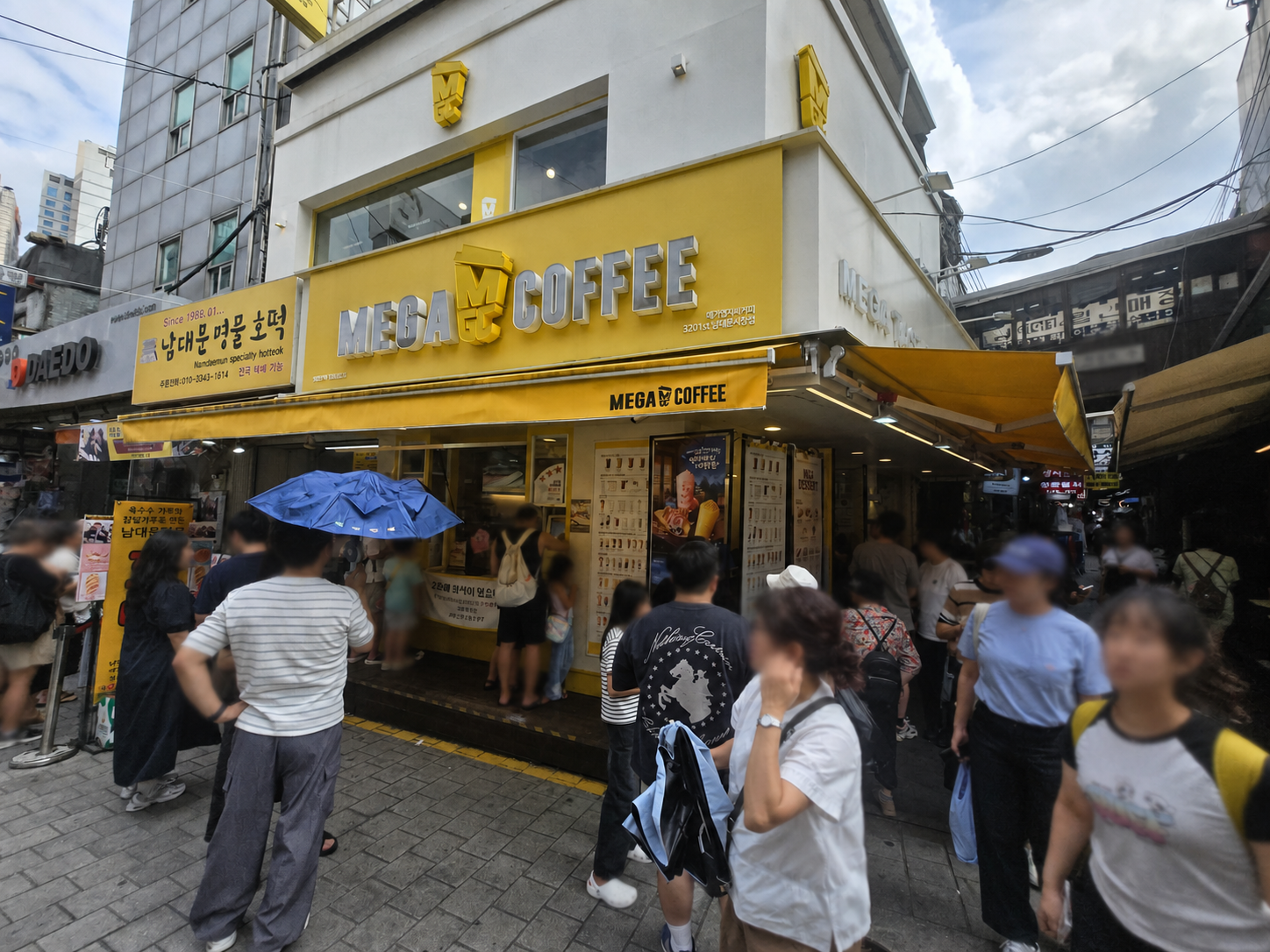 Crowded Namdaemun Market alley beside Mega Coffee and hotteok stalls