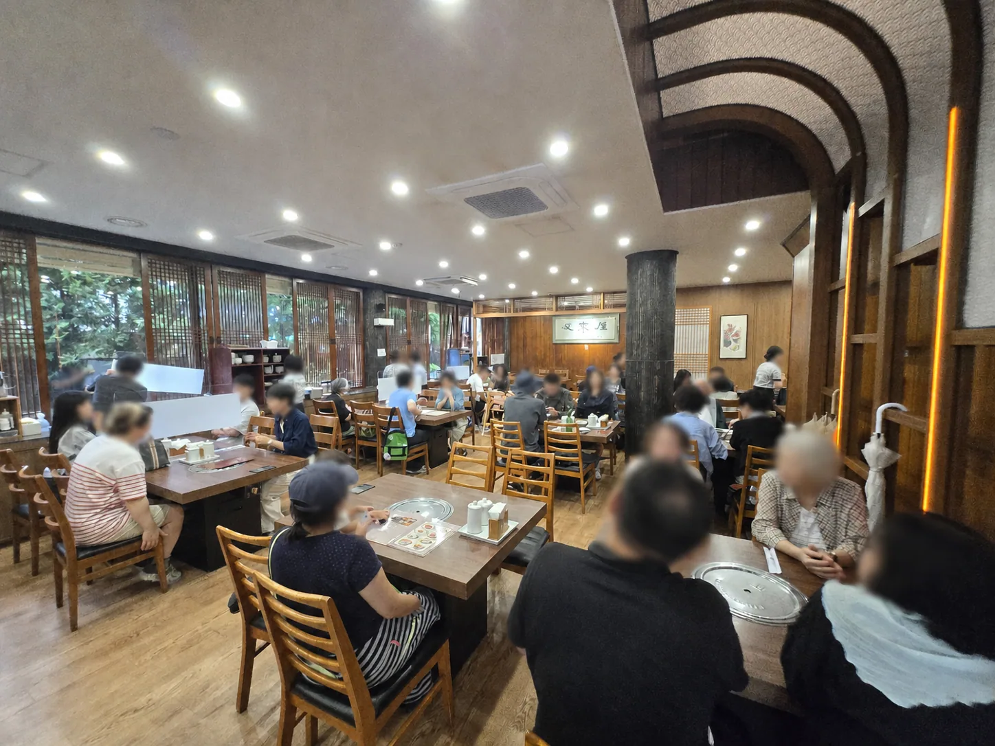 Busy dining room inside Woo Lae Oak with faces blurred for privacy