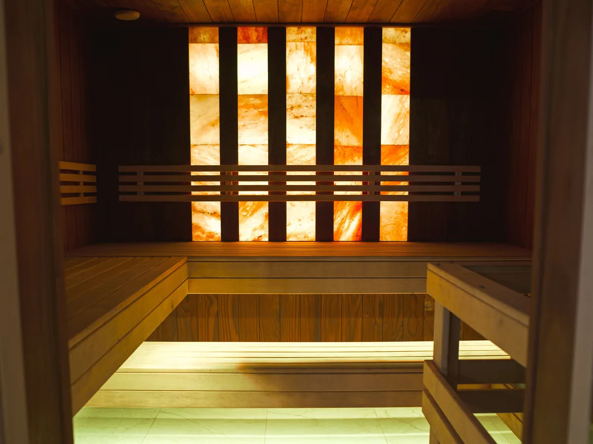 Warm wooden sauna room with an illuminated salt wall and benches