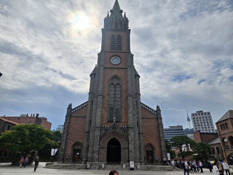 Myeongdong Cathedral front facade and bell tower under a cloudy Seoul sky