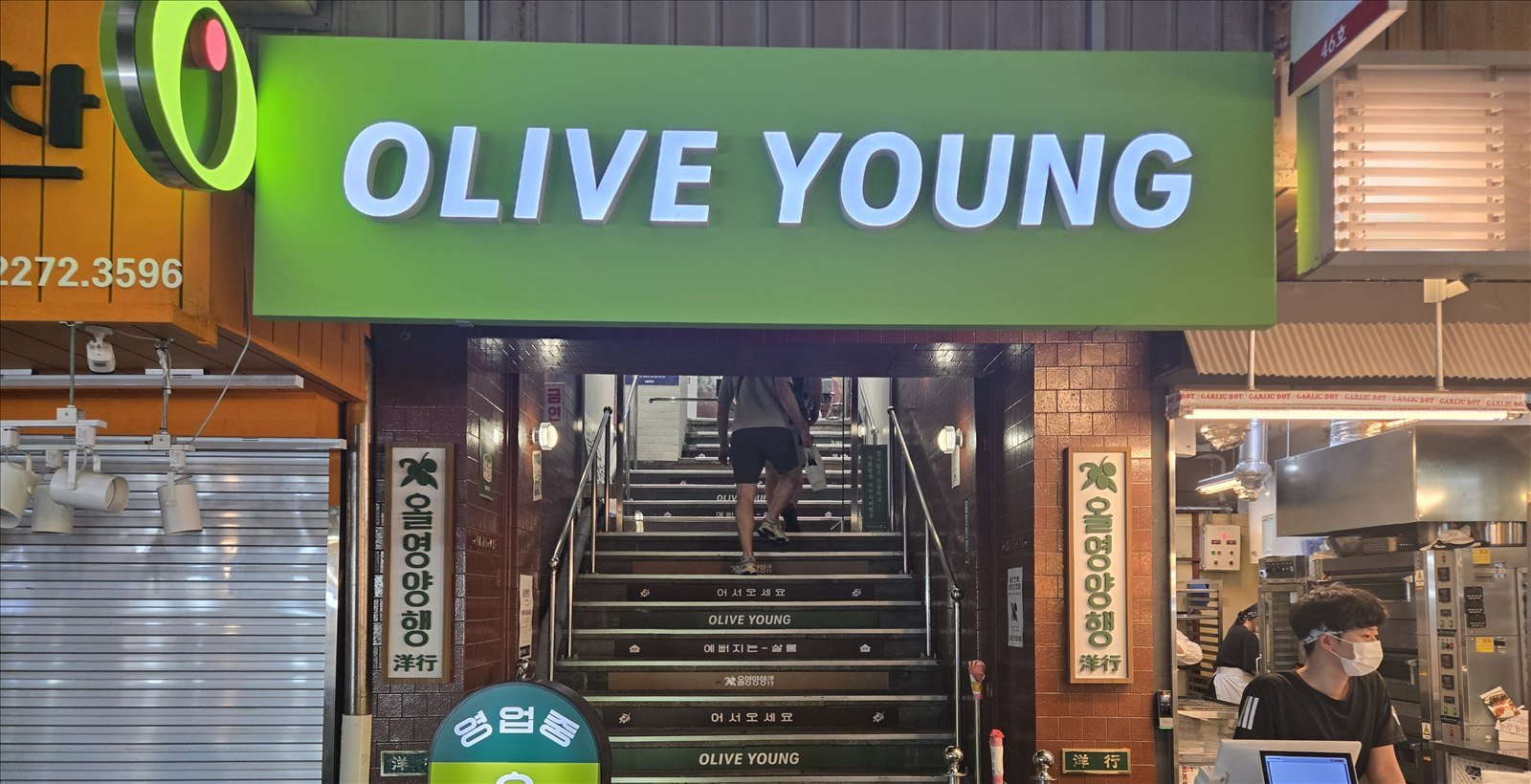 Olive Young entrance inside a Seoul market with stairs leading to the beauty store