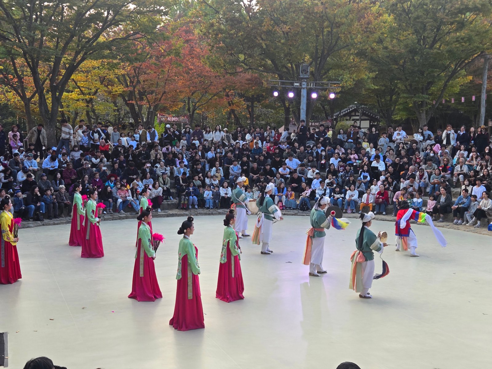Performers in colorful traditional dress in an outdoor arena at Korean Folk Village