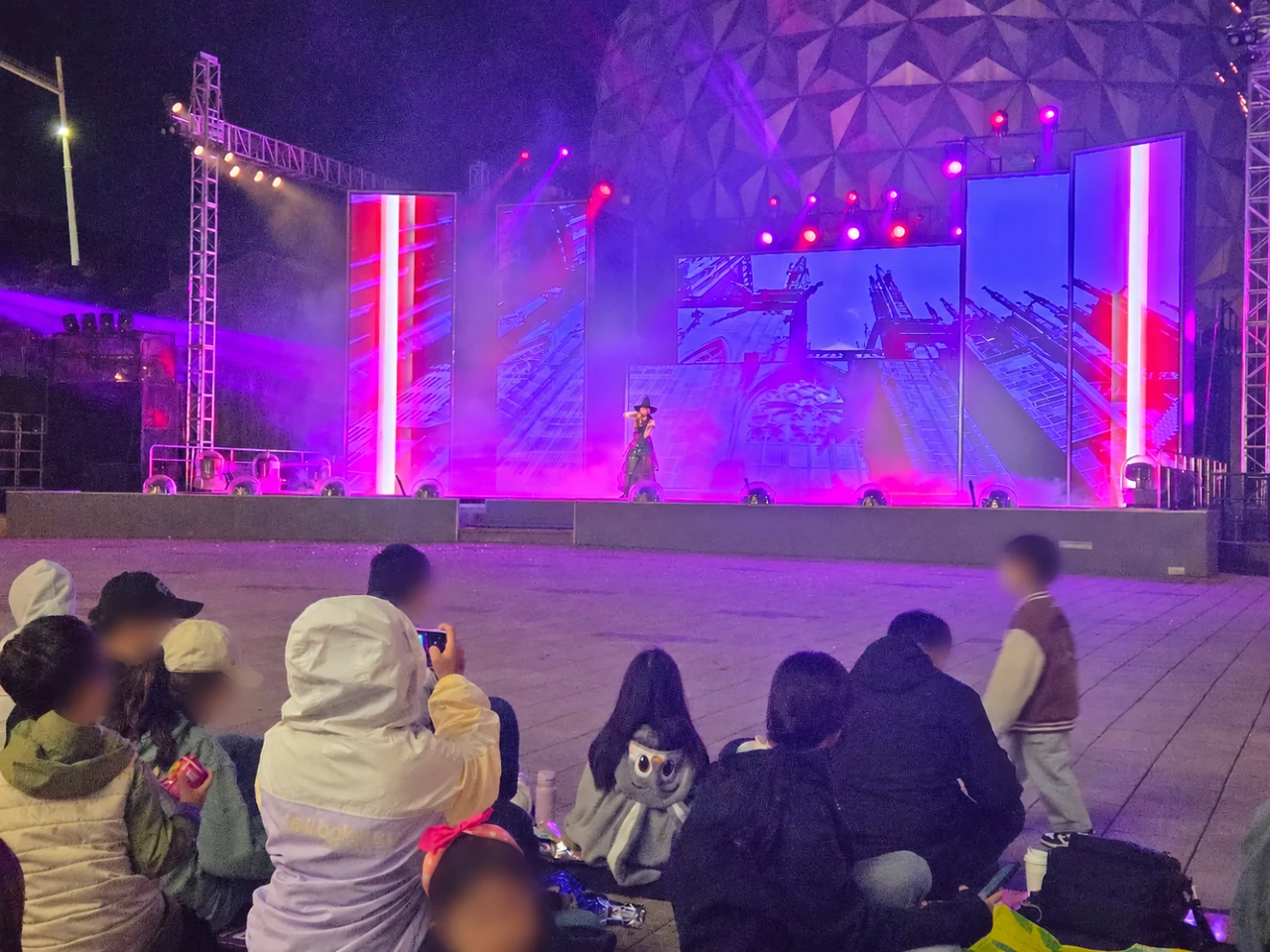 Nighttime performance at Seoul Land’s illuminated dome stage with spectator faces anonymized