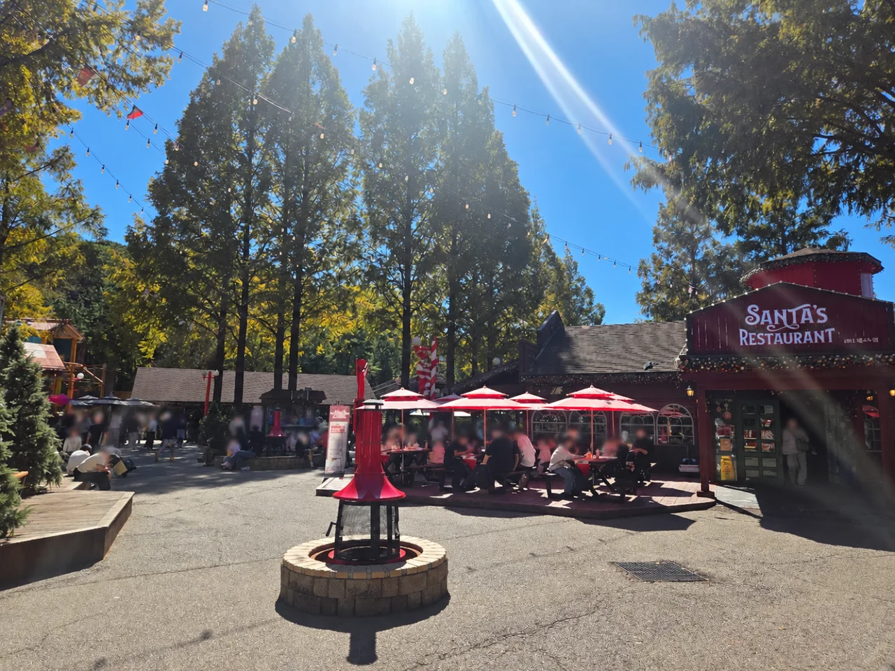 Red umbrellas and tree-lined seating beside Santa’s Restaurant at Seoul Land